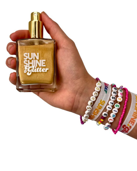 Hand holding a gold bottle with text on a computer screen with open tabs and icons.